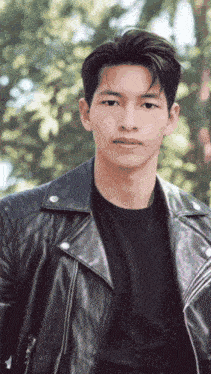 a young man wearing a black shirt and a leather jacket