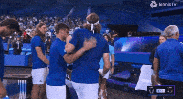 a group of tennis players hugging each other in front of a screen that says tennis tv
