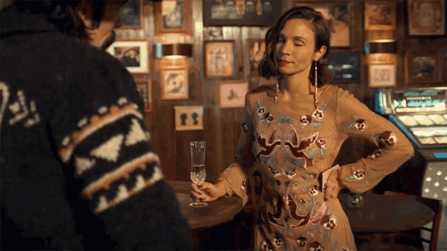 a woman in a dress holds a glass of champagne in front of a man