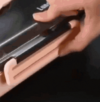 a close up of a person 's hand holding a black object .
