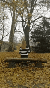 a woman in a striped sweater sits on a park bench