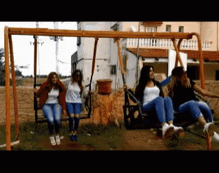 a group of girls are sitting on swings in a playground