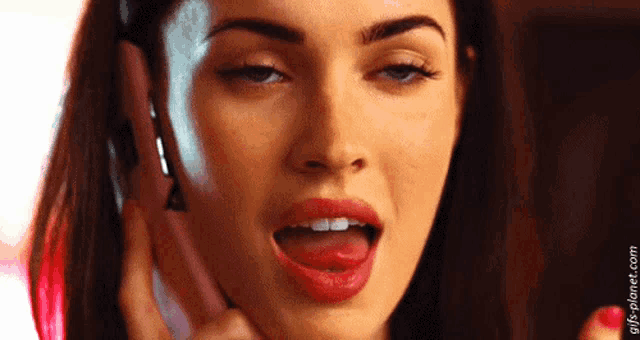 a woman is talking on a cell phone with her tongue out .