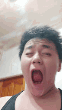 a man yawning with his eyes closed and his tongue sticking out