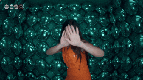 a woman in an orange dress covering her face with her hands