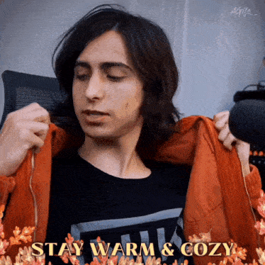 a young man is taking off his jacket with the words stay warm and cozy written on the bottom