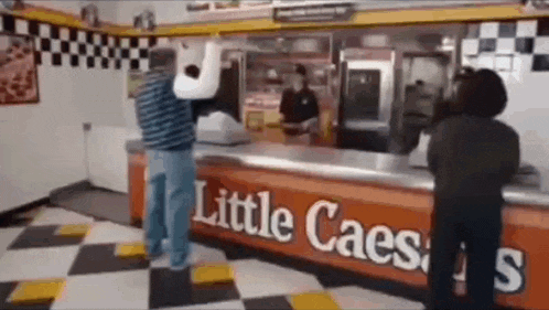 a man is standing in front of a little caesar 's sign .