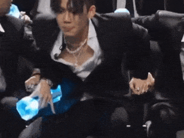 a man in a suit is sitting in a chair with a bottle of water .