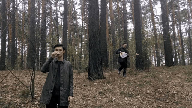 a man drinking from a cup in a forest