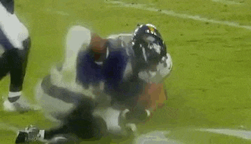 a football player is being tackled by another player on a field during a game .