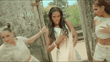 a woman in a white crop top is standing next to two other women in white shorts