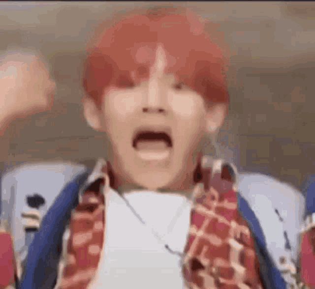 a man with red hair is making a funny face while sitting in a chair with his mouth open .