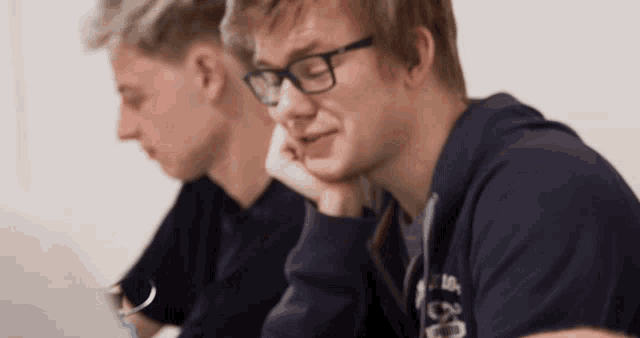 a man wearing glasses sits next to another man