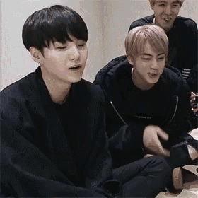 a group of young men are sitting on the floor in a room and talking to each other .