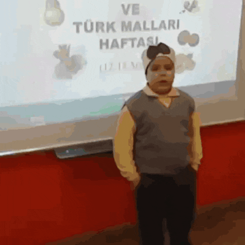 a young boy is standing in front of a screen that says ve turk mallari haftasi