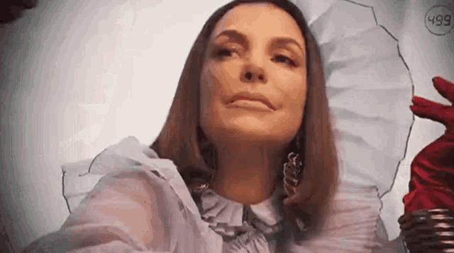 a woman wearing a white shirt and red gloves is looking at the camera .