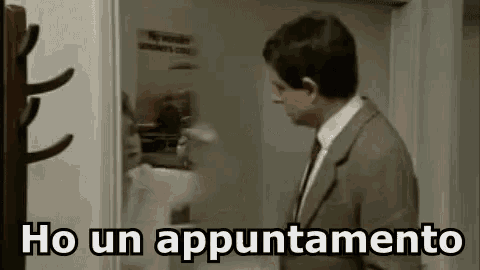 a man in a suit and tie is standing in front of a door and talking in a foreign language .