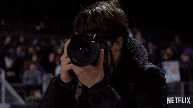 a man holding a nikon camera in front of a netflix logo