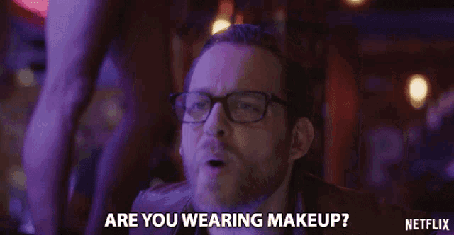 a man with glasses is asking if he is wearing makeup