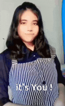 a girl in a striped shirt is standing in front of a wall and says `` it 's you ! ''