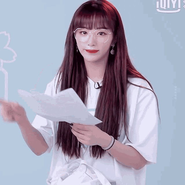 a woman wearing glasses holds a piece of paper in her hand