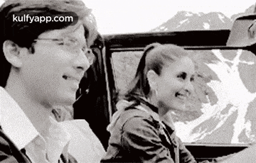 a black and white photo of a man and a woman sitting in a car .