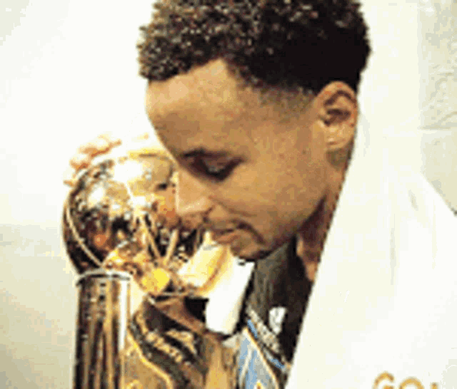 a man with a towel wrapped around his neck holds a trophy