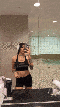 a woman is taking a picture of herself in a gym mirror with headphones on