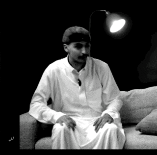 a man in a white robe is sitting on a couch under a lamp