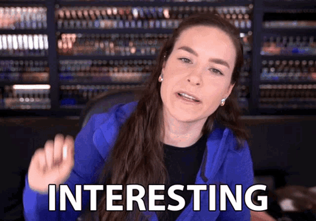 a woman in a blue jacket has the word interesting written on her face