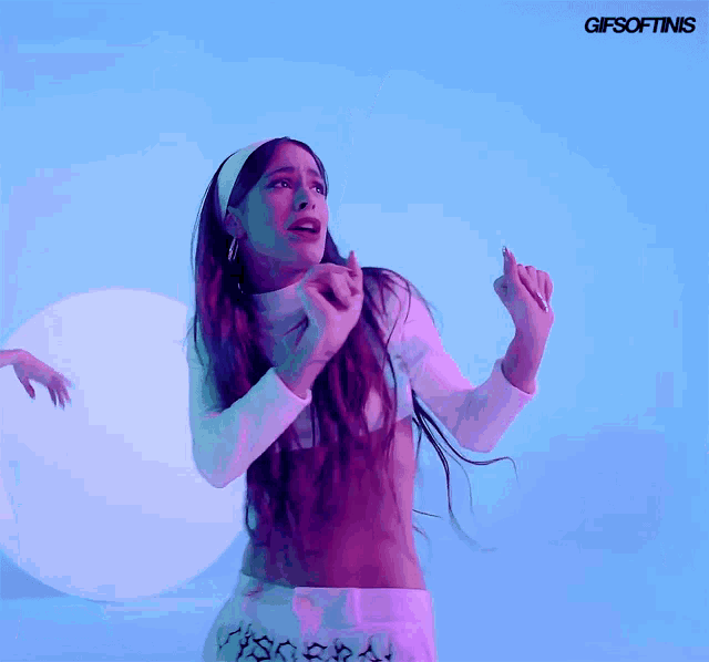 a woman with long hair is dancing in front of a blue background with the words gifsoftinis on it