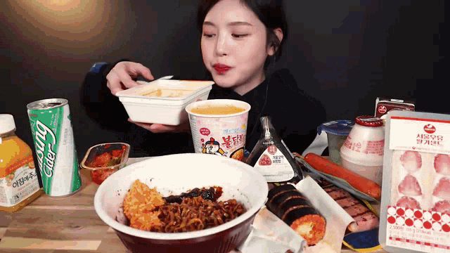 a woman is sitting at a table eating food and drinks including a can of ginger ale