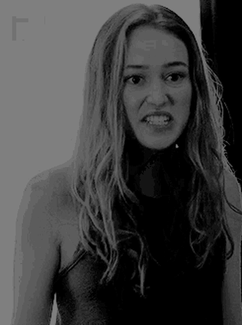 a black and white photo of a woman making an angry face .