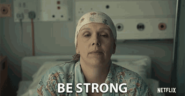 a woman in a hospital bed with the words be strong written on her face