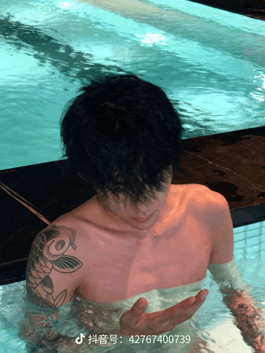 a shirtless man with a tattoo on his arm is in a pool