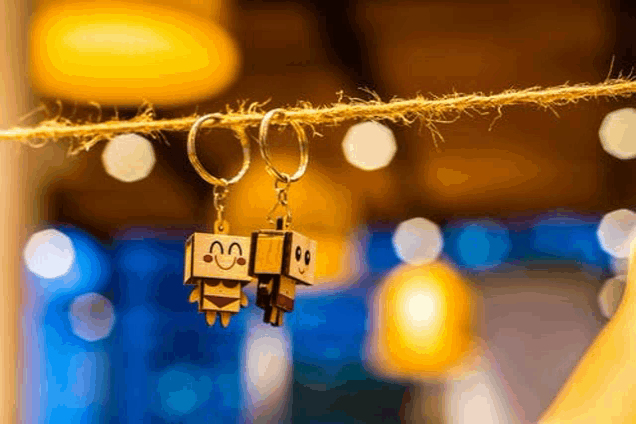 a pair of wooden keychains with faces on them are hanging on a string .