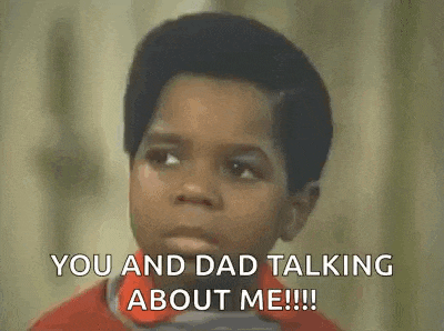 a young boy in a red shirt is talking to his dad .
