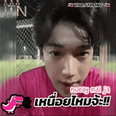 a young man in a pink shirt is behind a fence with t98 strong written on the bottom