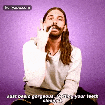 a man with long hair and a mustache is making a funny face while cleaning his teeth .