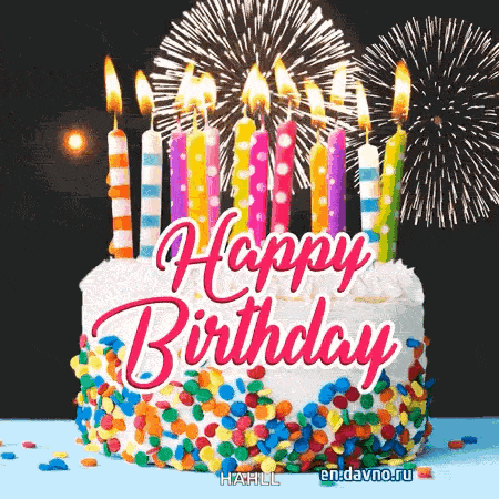 a birthday cake with candles and fireworks behind it .