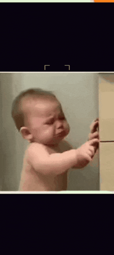 a baby is crying while playing with a piece of wood .