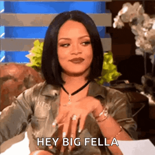 a woman is sitting on a couch with her hands on her hips and says hey big fella .