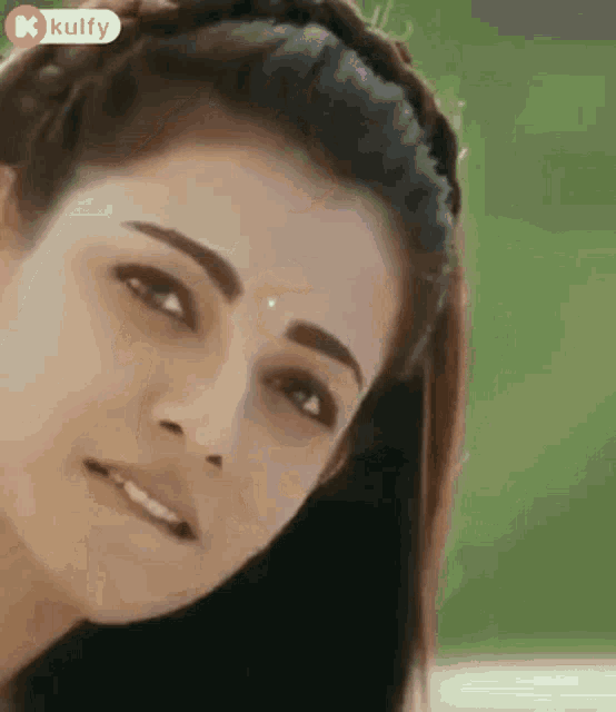 a close up of a woman 's face with a bindi on her forehead and a smile on her face .