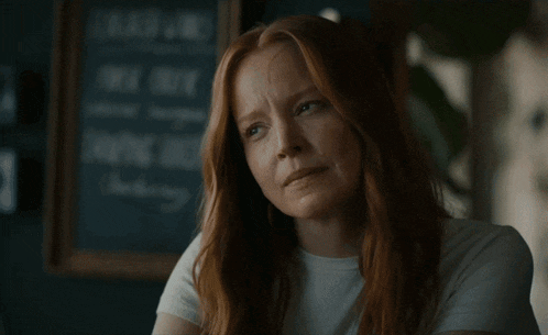 a woman with red hair has her eyes closed in front of a sign that says " free wifi " on it