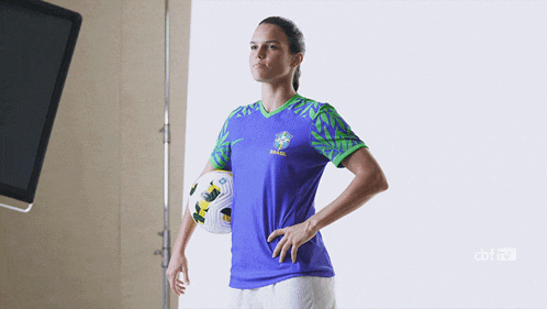 a woman holding a soccer ball wearing a purple shirt that says ' brasil ' on it