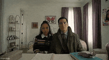 a man and a woman are sitting at a table in a room .