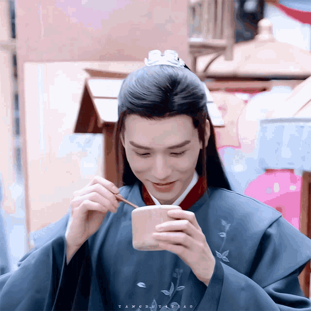 a man with long hair is eating from a small bowl