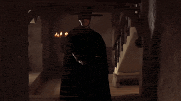 a man in a black cape and mask holds a torch