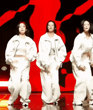 three women in white clothes are dancing on a stage .