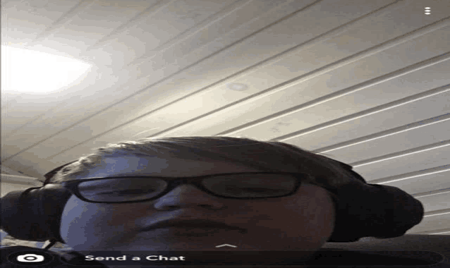 a boy wearing glasses and headphones has a send a chat button on the bottom right